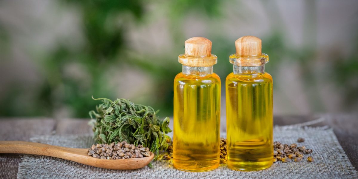 Bestes CBD-Öl: zwei Fläschchen und Hanfsamen auf Holzlöffel